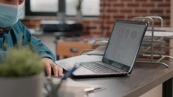 Close up of employee working with laptop and charts files video