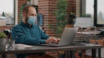 Portrait of entrepreneur with face mask using laptop video