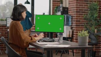 Employee looking at horizontal green screen on computer