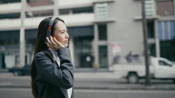 mujer de negocios, ambulante, escuchar música, con, placer, al lado de la calle, en, ciudad video