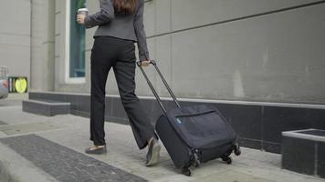 Businesswoman walking with a suitcase on the sidewalk video
