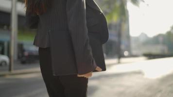 Woman in a black suit walking on the sidewalk carrying a laptop to work video