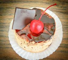 Cake with Cherries and Chocolate, Cupcake on Wood Background. photo