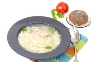 Chicken stock with slice of meat and noodles in black plate. photo