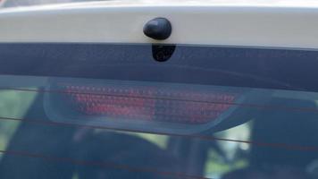 Rear window of a dusty white car with a stoplight behind glass, close-up. Red signals indicating vehicle braking. They turn on automatically when you press the brake and turn off when you release it. photo