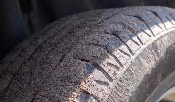 Dirty car wheel on a soil road to the countryside. Close-up detail of a tire. Transport, driving and car concept. The car got stuck in the sand. photo