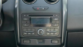 Established multimedia in the car. Close-up of the head unit and radio receiver with display inside the car. Dust and scratches are visible on the device screen. Multimedia system. photo