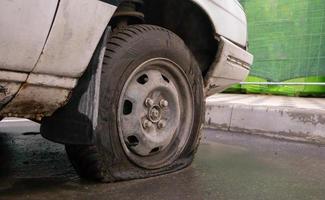 Coche abandonado viejo roto con ruedas planas. un neumático con un pinchazo. el concepto de accidente, avería, reparación, seguro. un pinchazo en la rueda de un coche. Ucrania, Kiev - 19 de agosto de 2021. foto