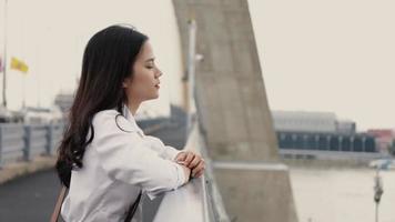 giovane donna asiatica in piedi sul ponte. video