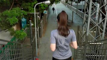 Atleta de mulher asiática usando fones de ouvido, ouvindo música em um viaduto na cidade. video
