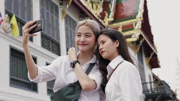 sonrientes mujeres asiáticas que usan teléfonos inteligentes tomando selfies una foto. video