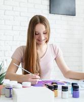 Artista de mujer sonriente pintando sobre ropa en su estudio foto