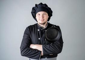 Male chef holding a saucepan isolated on gray background