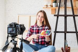 Woman making a video for her blog on art using a tripod mounted digital camera photo