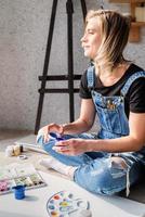 hermosa mujer artista pintando un cuadro en casa foto