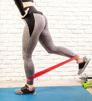 woman exercising legs at home using rubber resistance band photo