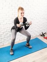 young fit woman doing squats with dumbbell photo