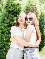 Happy girlfriends hugging together outdoors in the park photo