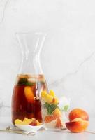 Iced cold peach tea with fruit slices and mint photo