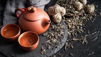 Asian teapot and green tea on slate plate