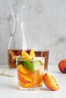 Iced cold peach tea with fruit slices and mint