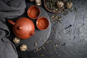 Asian teapot and green tea on slate plate top view flat lay