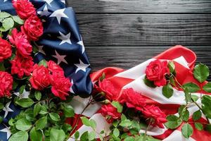 Red roses over the USA flag on dark wooden background top view flat lay photo
