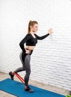 woman exercising legs at home using rubber resistance band photo