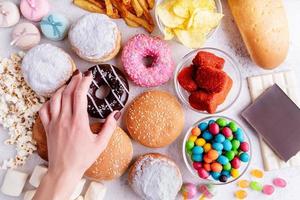 comida poco saludable y comida rápida con rosquillas, chocolate, hamburguesas y dulces vista superior foto