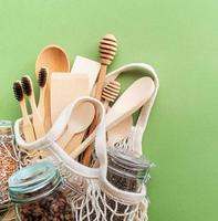 Zero waste eco friendly bag and wooden tools top view on green background photo