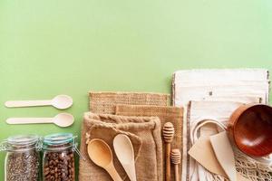 Zero waste eco friendly bags and wooden tools top view on green background photo