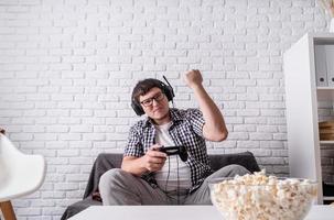 Emocionado joven jugando videojuegos en casa disfrutando de su victoria foto