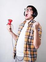 Funny young man screaming playing video games holding a joystick isolated on gray background photo