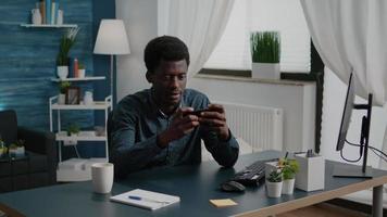 Cheerful happy black man playing video games on his phone