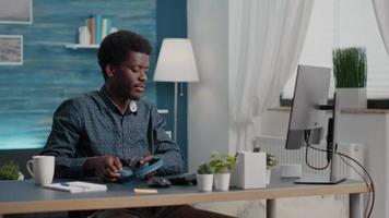 African american ethnicity freelancer putting headphones on working from home, remote worker computer user in home office video
