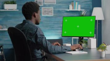African american man using and typing on mockup computer with green screen video