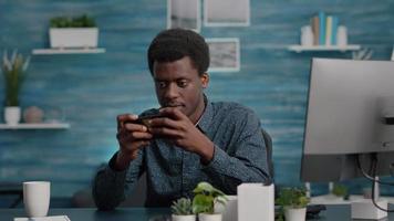 Afro-Amerikaanse man die videogames speelt op zijn telefoon video