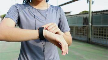 Atleta de mulher asiática olhando para a frequência cardíaca em um smartwatch. video