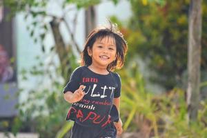 a little girl is having fun and running. A sincere smile on the face of a malay toddler girl. photo