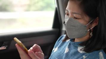 mujer con máscara y usando un teléfono inteligente mientras está sentado en el coche video