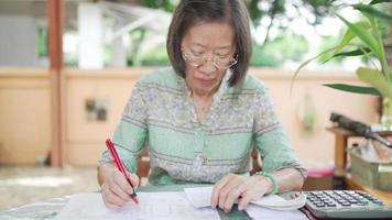 Mujer mayor calcula el saldo de ingresos y gastos en casa