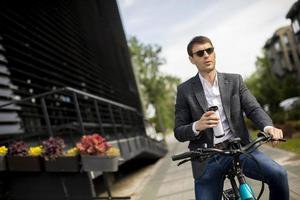 Young businessman on the ebike with takeaway coffee cup photo