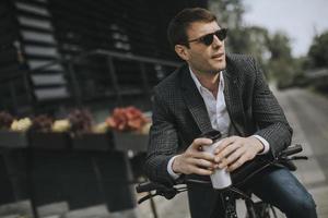 Young businessman on the ebike with takeaway coffee cup photo