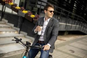 Young businessman on the ebike with takeaway coffee cup photo