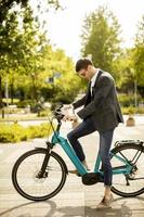 Young businessman on the ebike with takeaway coffee cup photo