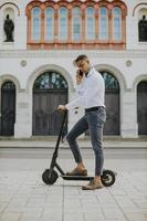 Joven afroamericano mediante teléfono móvil mientras está de pie con scooter eléctrico en una calle