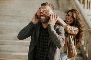 mujer joven que cubre los ojos de su novio en el parque foto