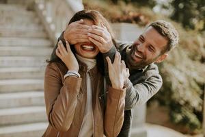 Young man covering the eyes of his girlfiend in the park photo