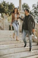 Young couple smiling and talking while strolling down outdoor stairs on autumn day photo