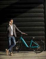 Young businessman standing by the ebike and using mobile phone photo